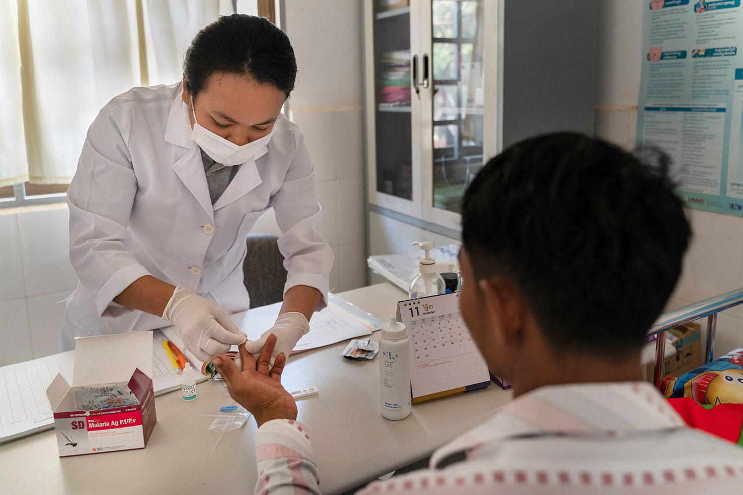 Woman prepares to perform a malaria rapid diagnostic test for a patient.
